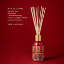 A red diffuser with a gold-colored base, filled with white sticks, against a red background.